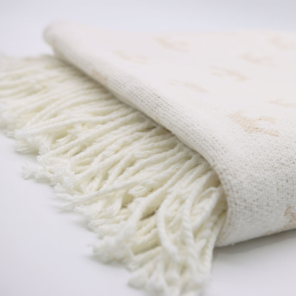 white knitted blanket from domsoeiro with fringes on bottom on a bright background