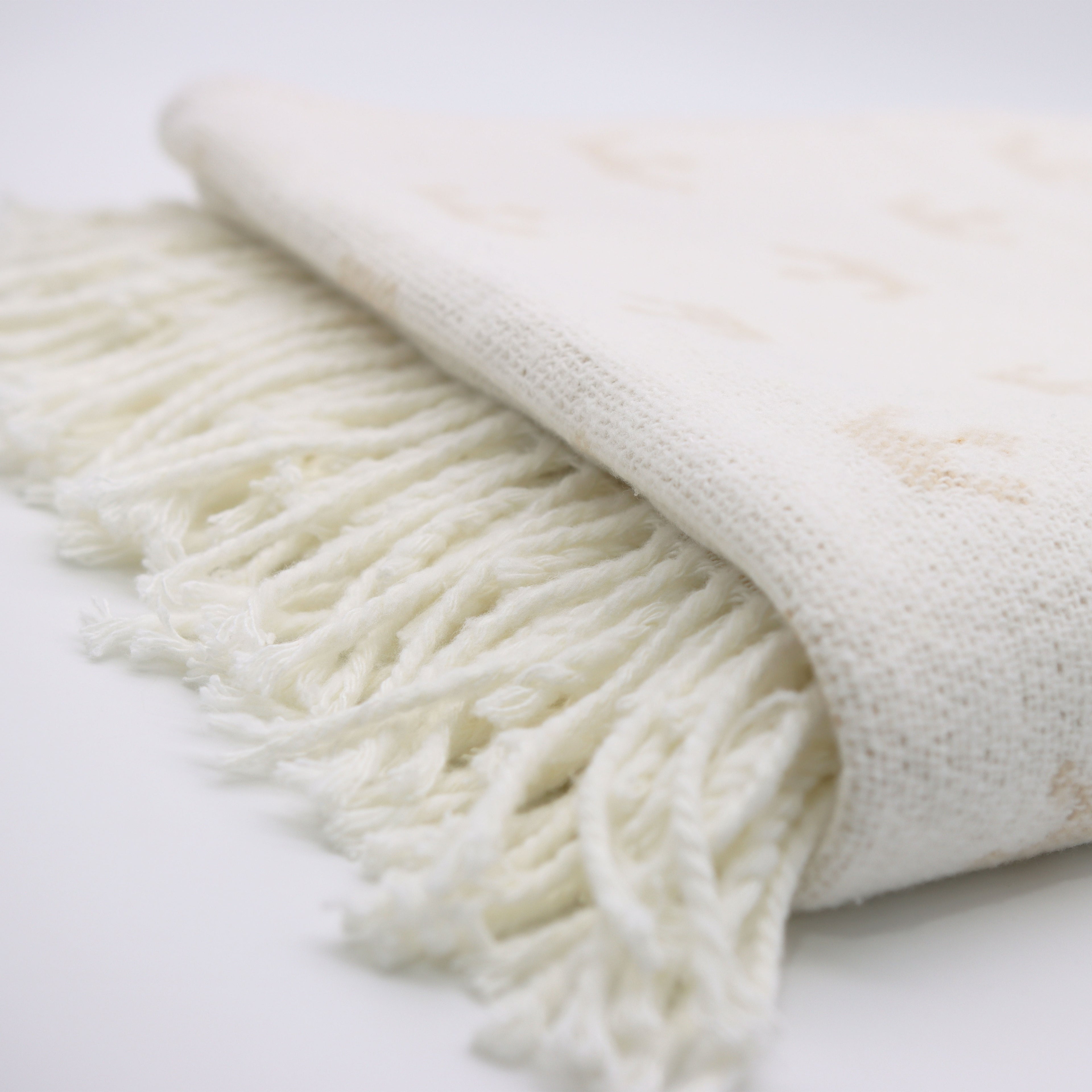 white knitted blanket from domsoeiro with fringes on bottom on a bright background