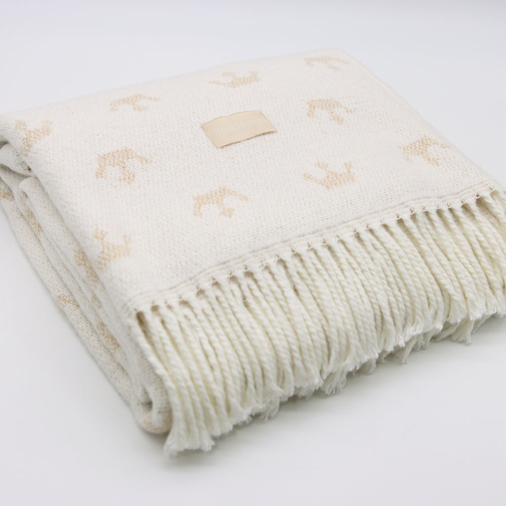 folded large white blanket with beige crowns and fringes at the bottom