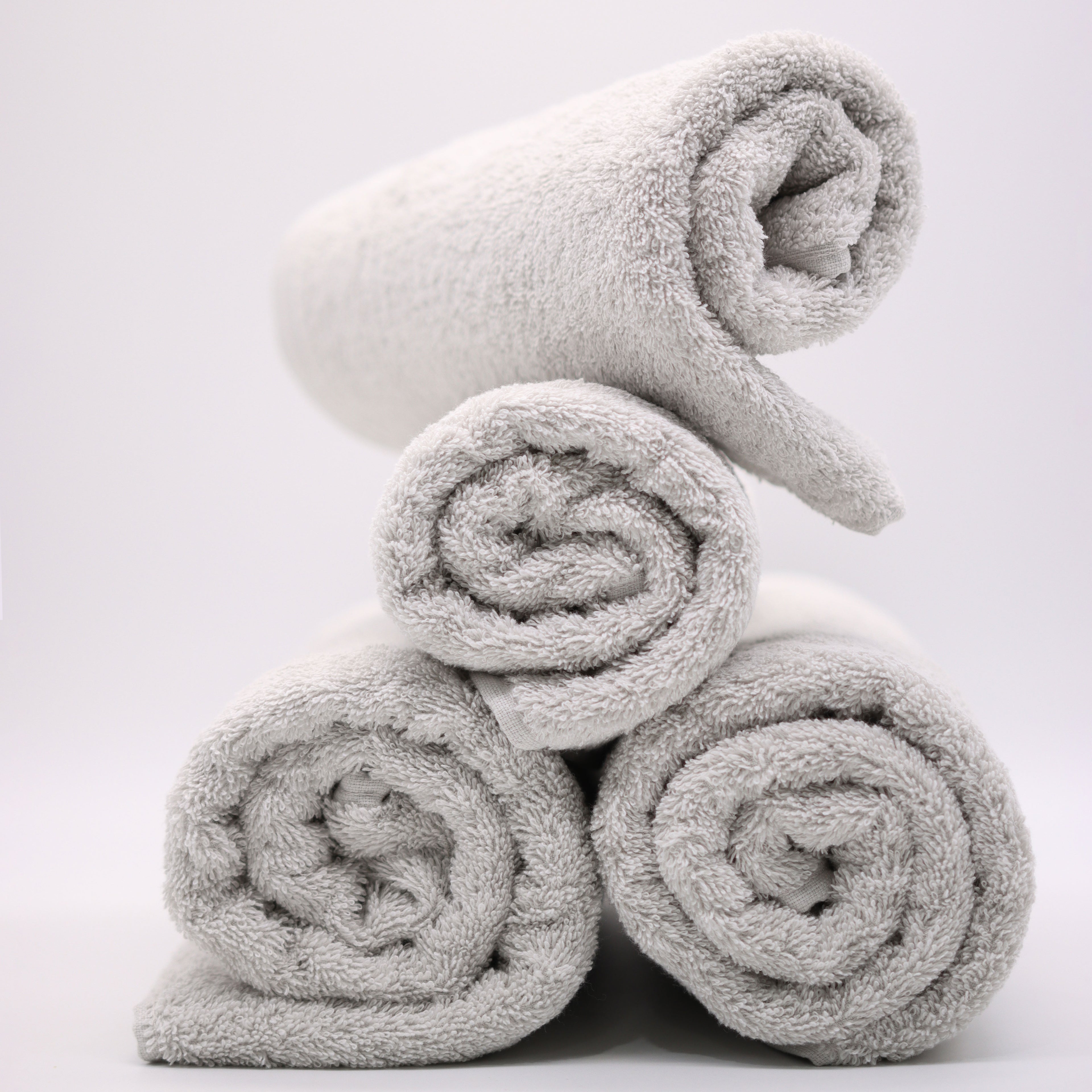grey towels folded in rolls on top of each other