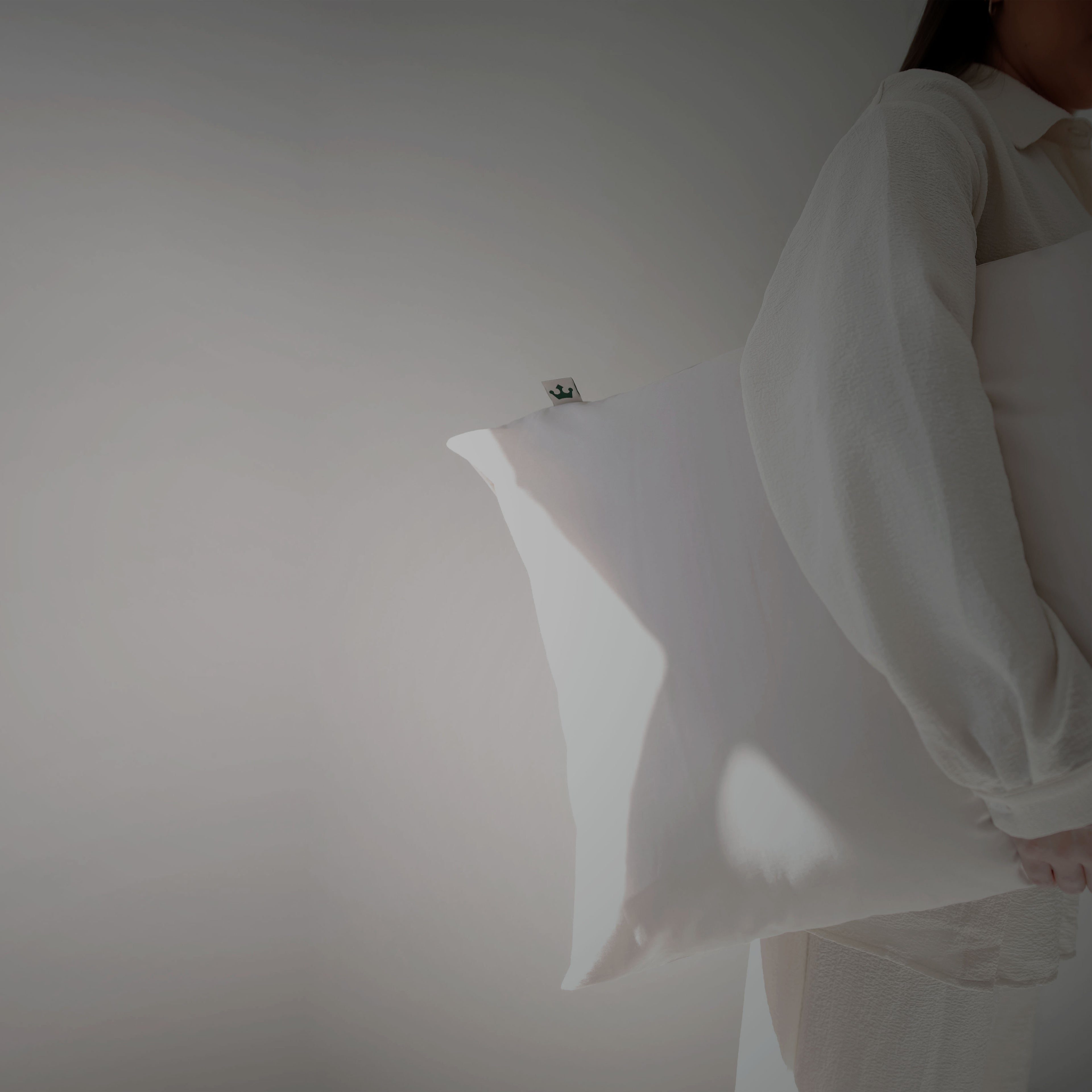 Person holding a white pillow against a plain background