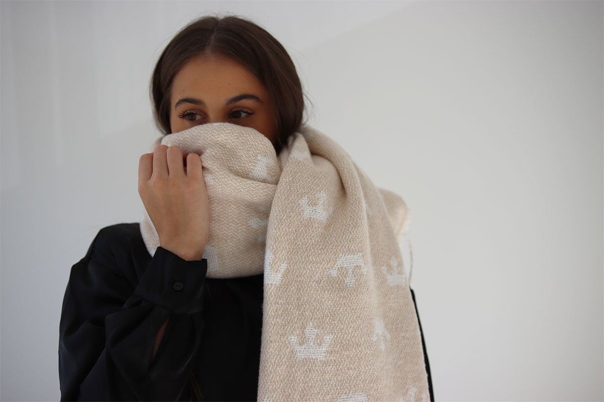 Person wearing a beige patterned scarf against a plain background
