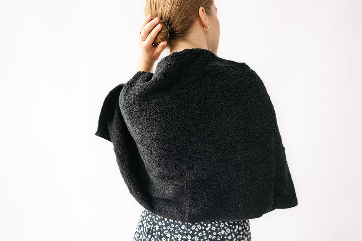 Woman wearing a black towel over her shoulders on a white background