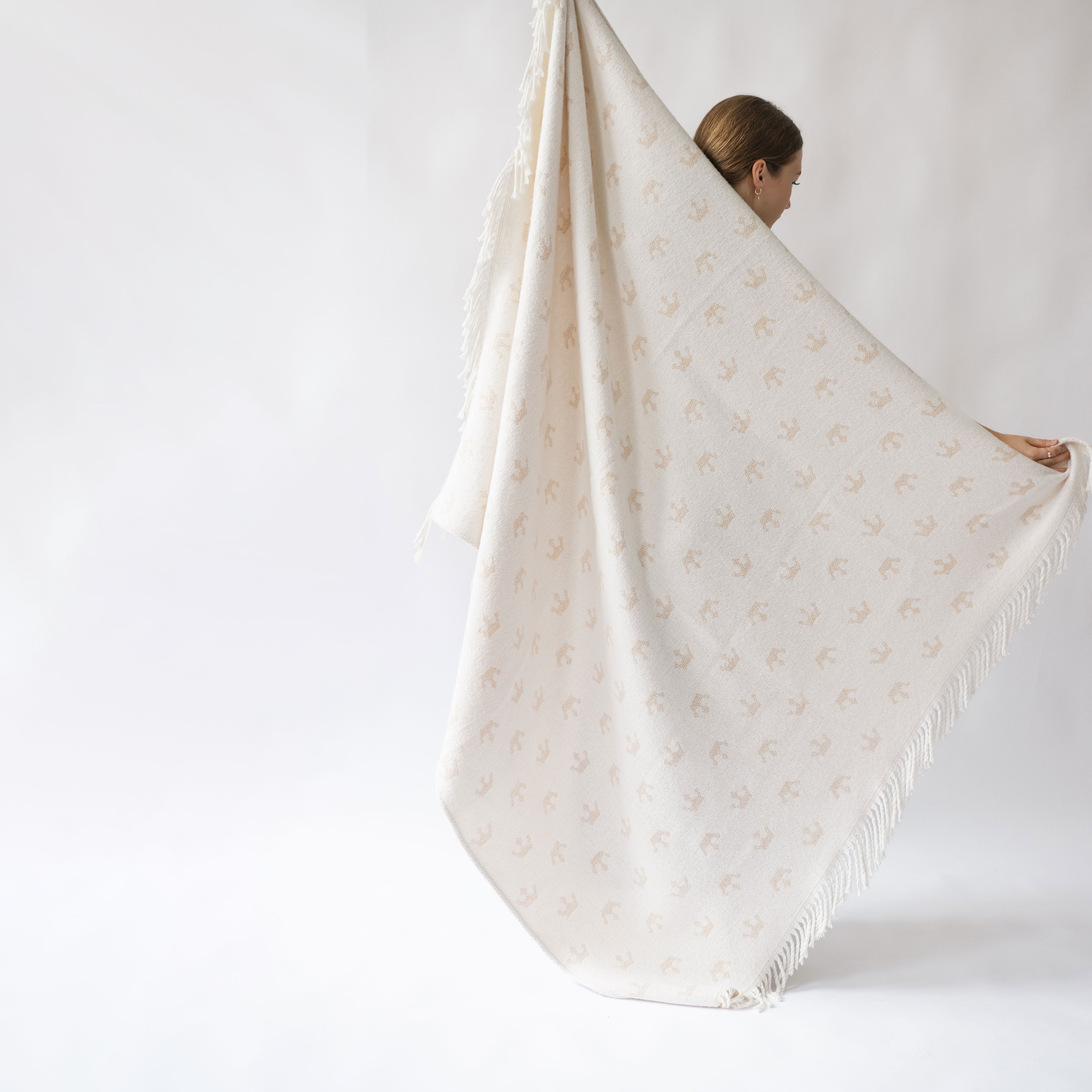 girl holding a large blanket with a pattern of crown and a white and bright background