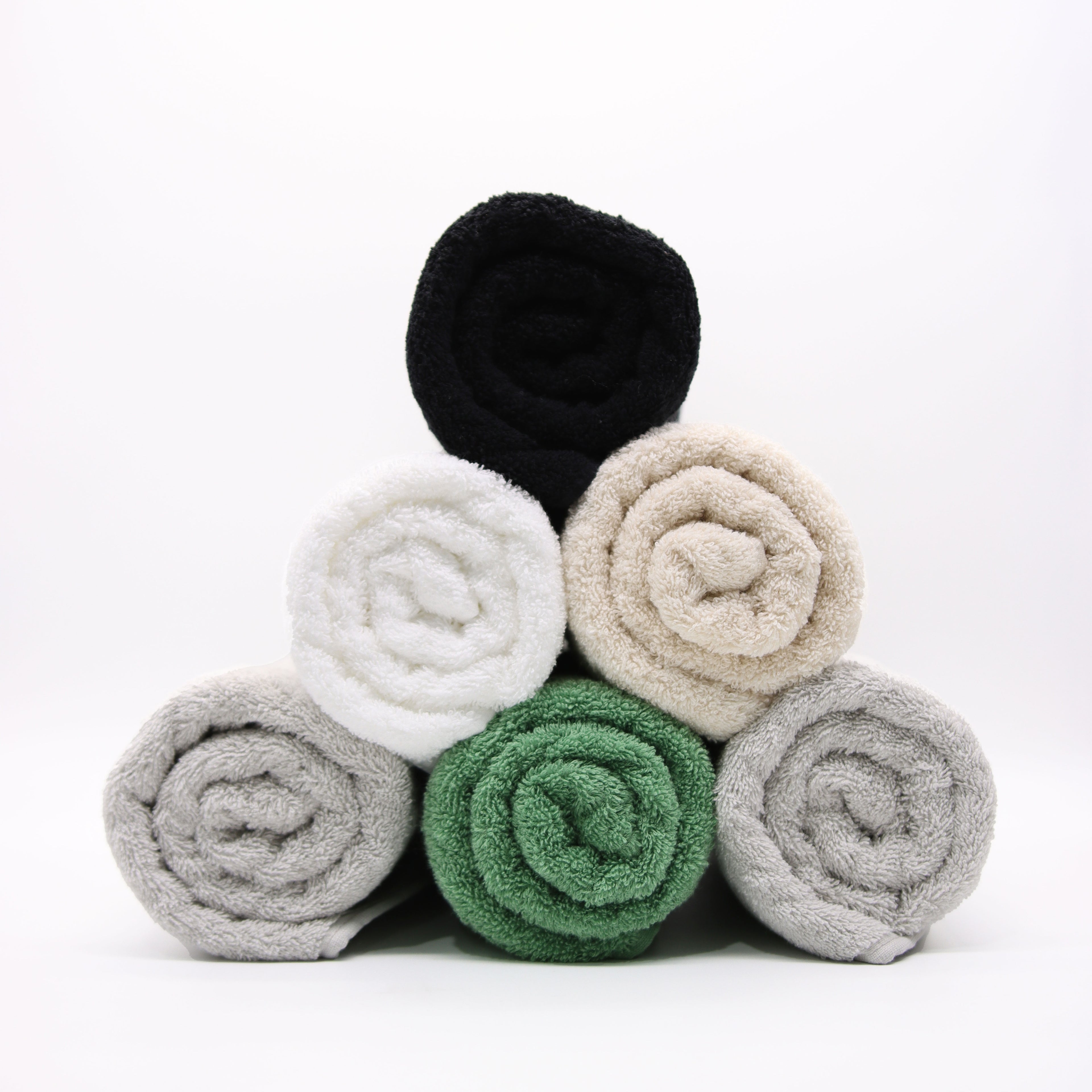 Stack of rolled-up towels in black, white, beige, green, and gray on a white background