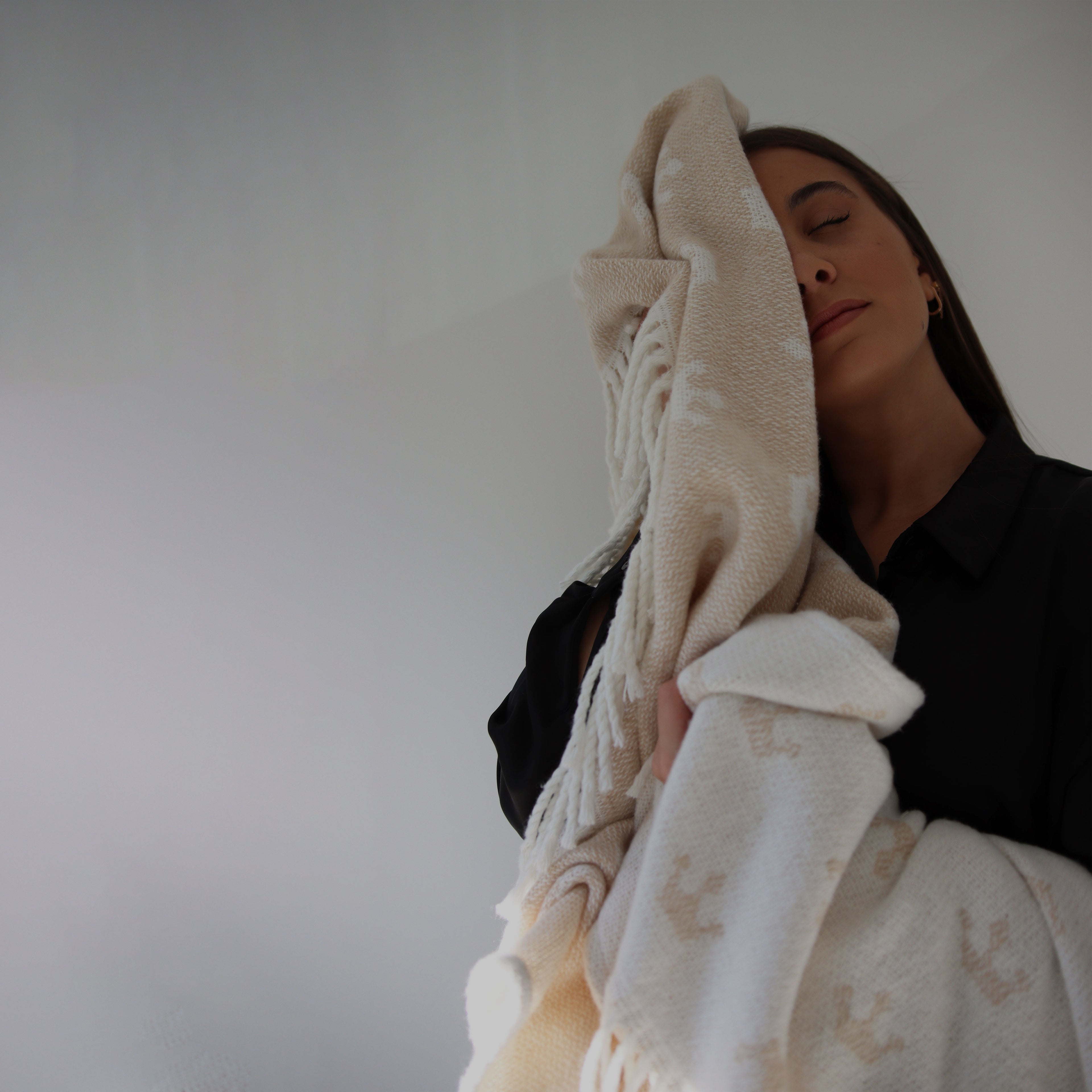 Woman holding a beige textured blanket against a plain background