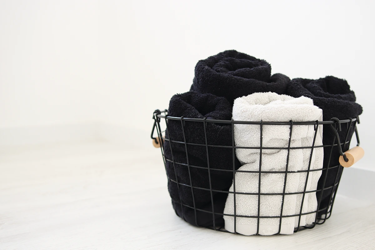 black basket with grey and black towels from domsoeiro is a white room