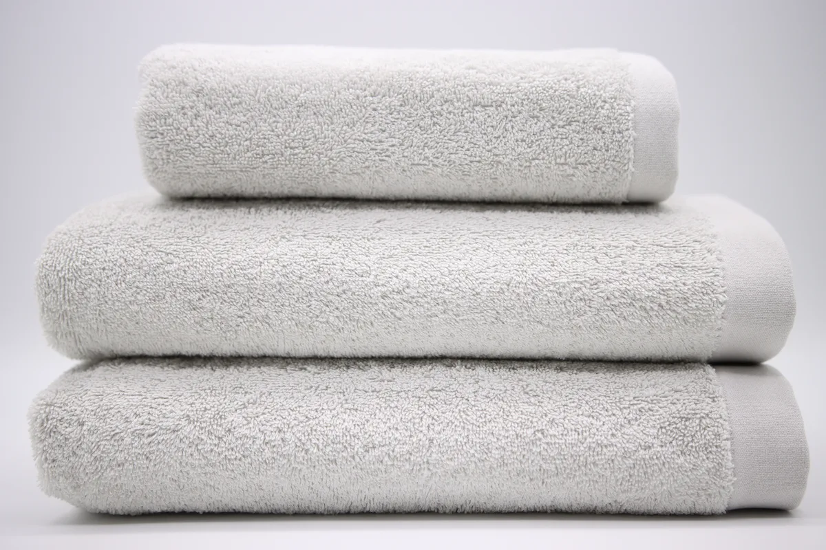 Ein Set von drei grauen Handtüchern, zwei in Badegröße und eines in Handtuchgröße.