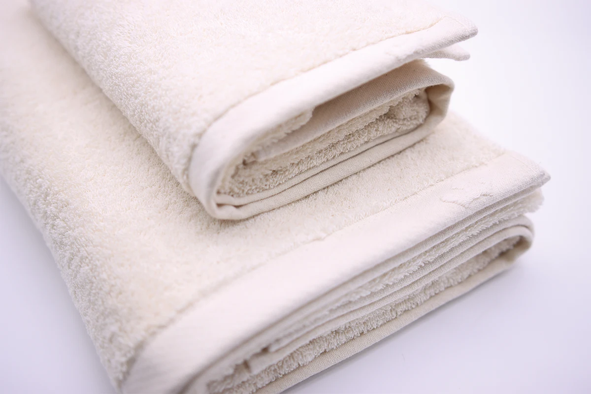 Como fazer as tuas toalhas ficarem macias sem usar uma secadora. Duas toalhas bege dobradas da Domsoeiro.