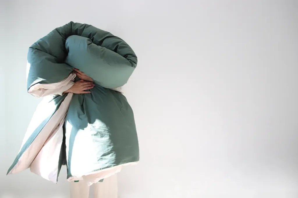 Person, die eine dunkelgrüne Bettdecke von DomSoeiro umarmt