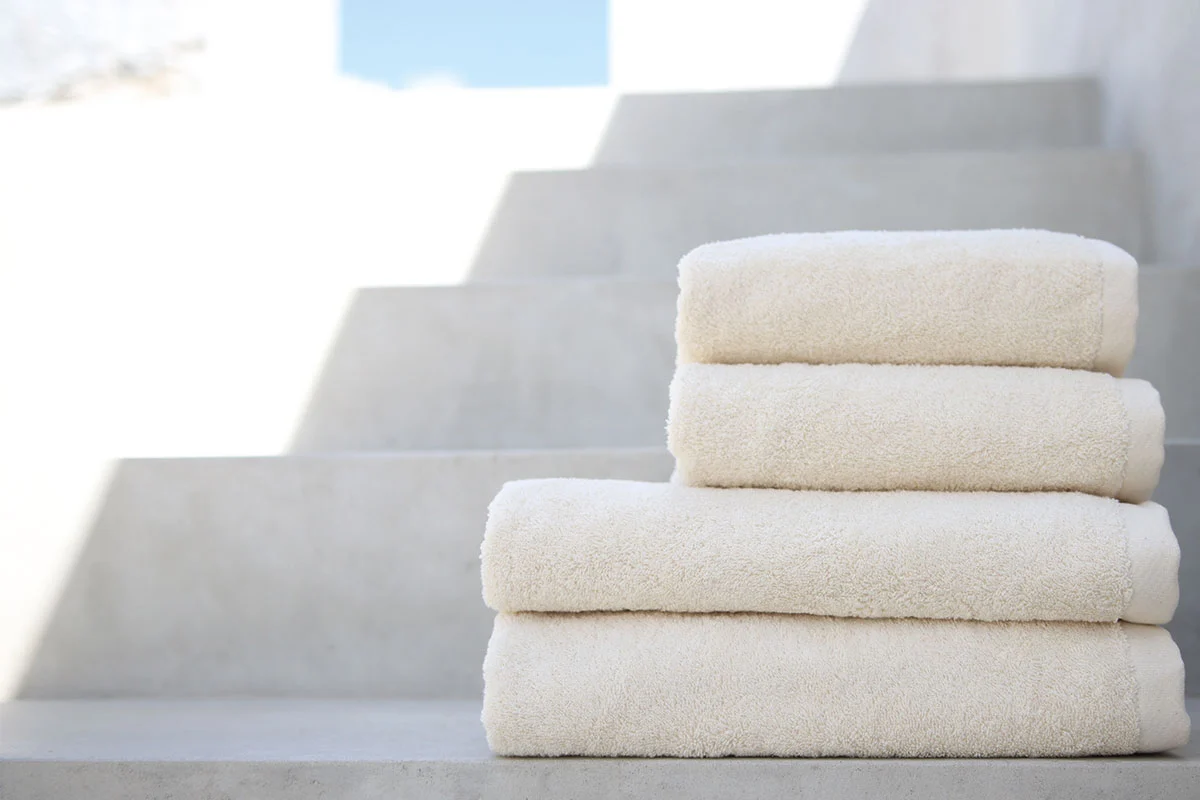 cuatro toallas beige de Domsoeiro dobladas encima de unas escaleras