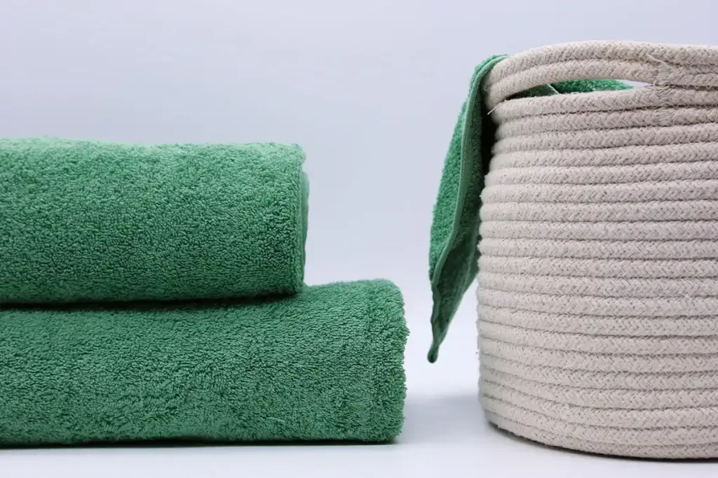 Wie man die beste Farbe für seine Badetücher wählt - gefaltete grüne Handtücher | zwei jadegrüne Handtücher gefaltet und in einen Korb gelegt